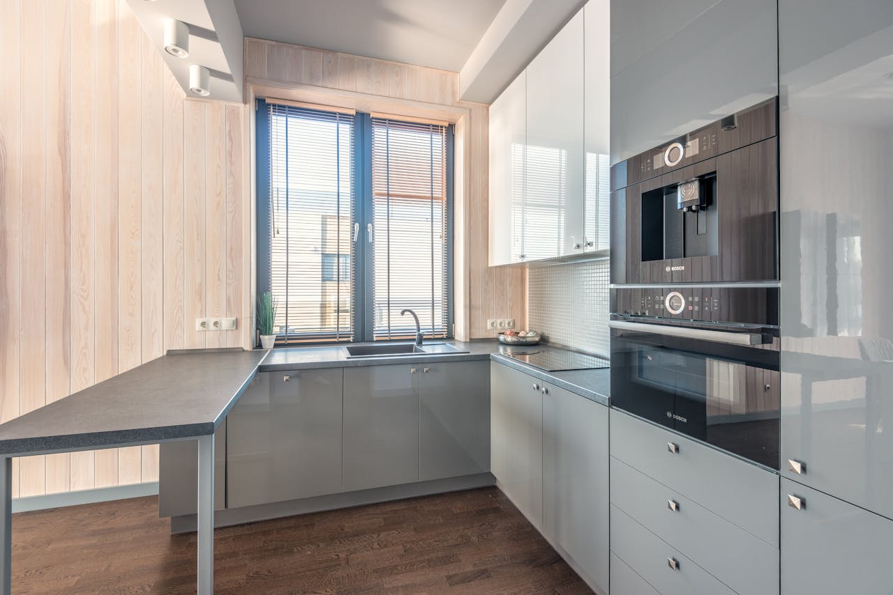 Stylish modern kitchen interior with sleek cabinets and natural light through a large window.